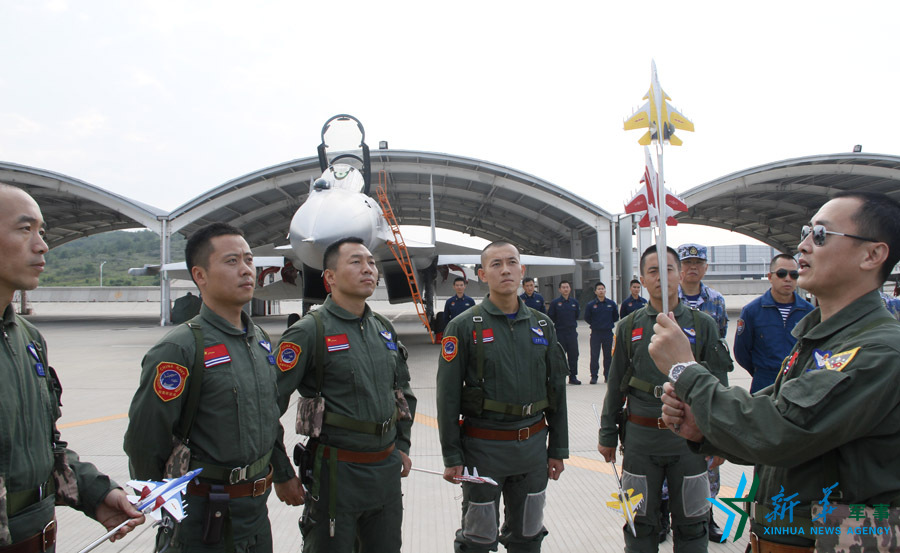 ↑艦載航空兵某部司令員戴明盟向飛行員演示空中飛行注意事項。