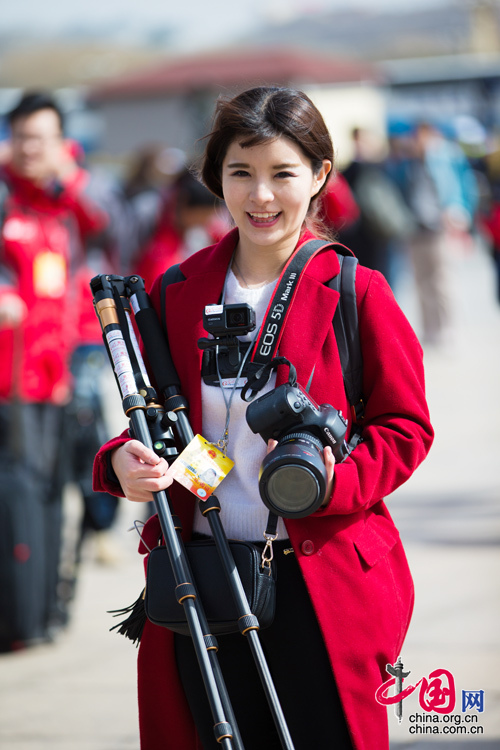 2016年兩會，人民大會大堂前，一位笑容燦爛的紅衣女記者正步入大會堂。中國網 鄭亮 攝
